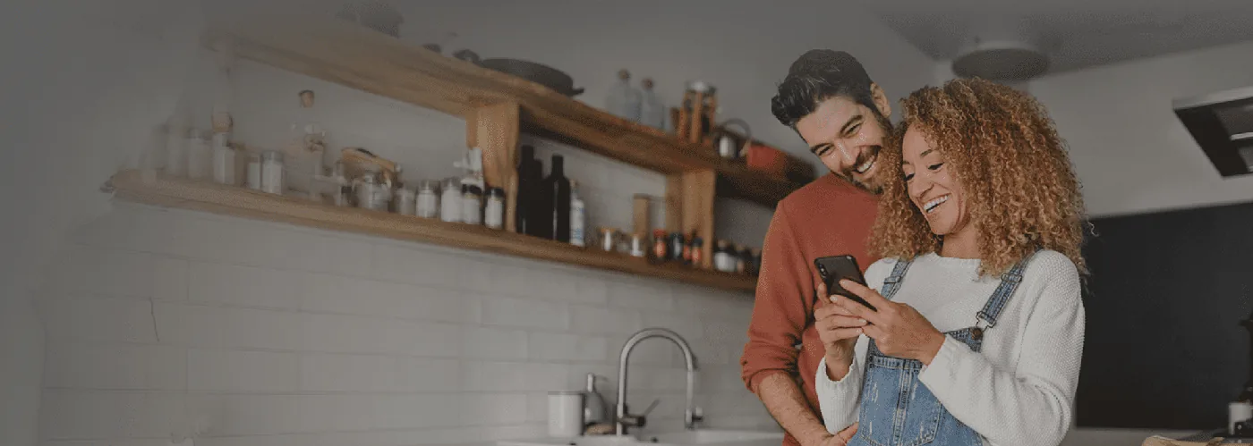 A smiling couple looking at their phone together at home