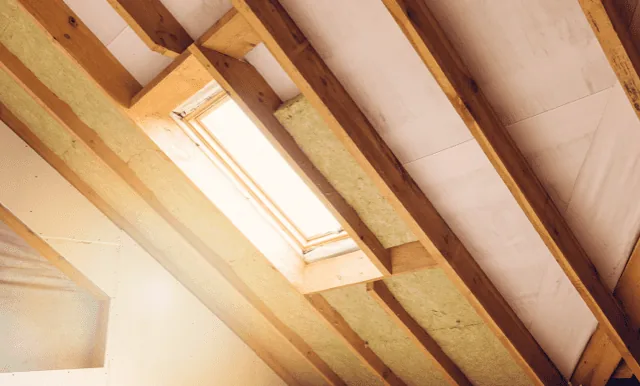 Insulation fitted around a roof window between sloping roof timbers